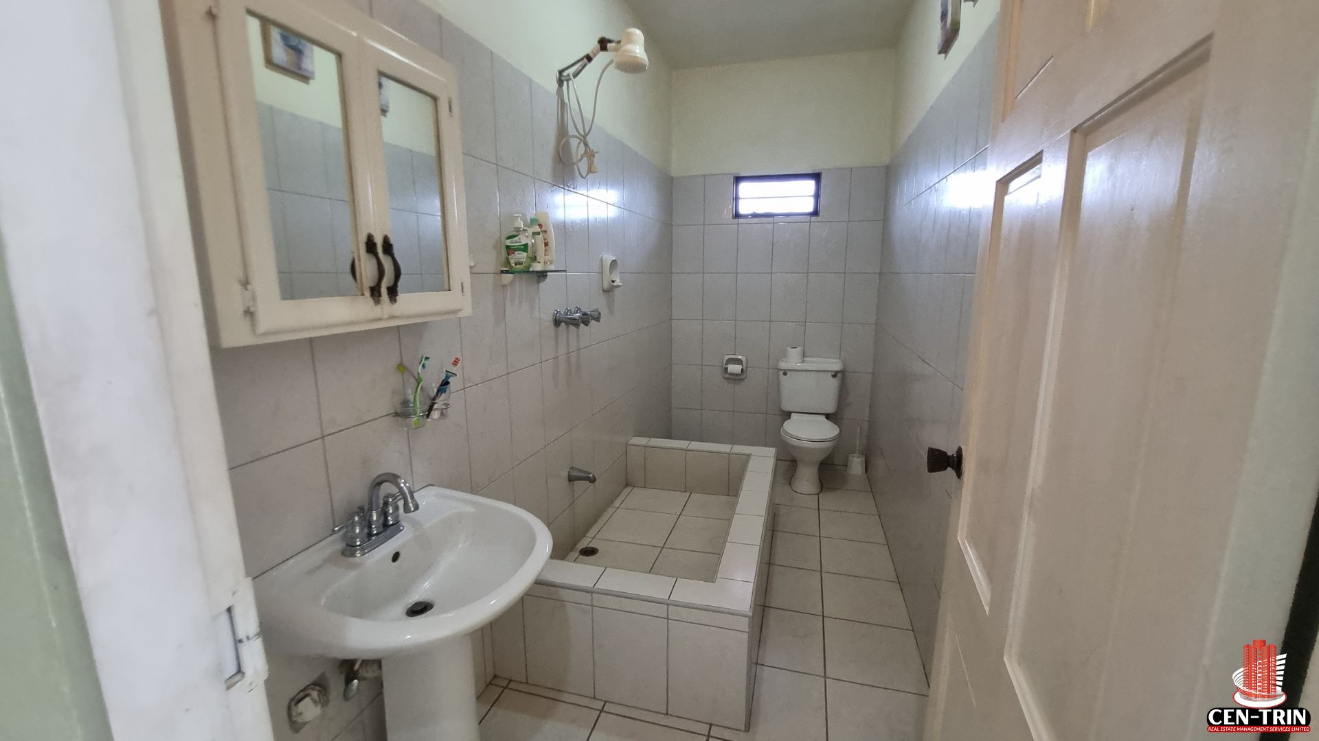 Bathroom in a Home For Sale in Trinidad, with a pedestal sink, tiled shower/bath, and toilet, part of the property's potential for semi furnished units and rental investment.