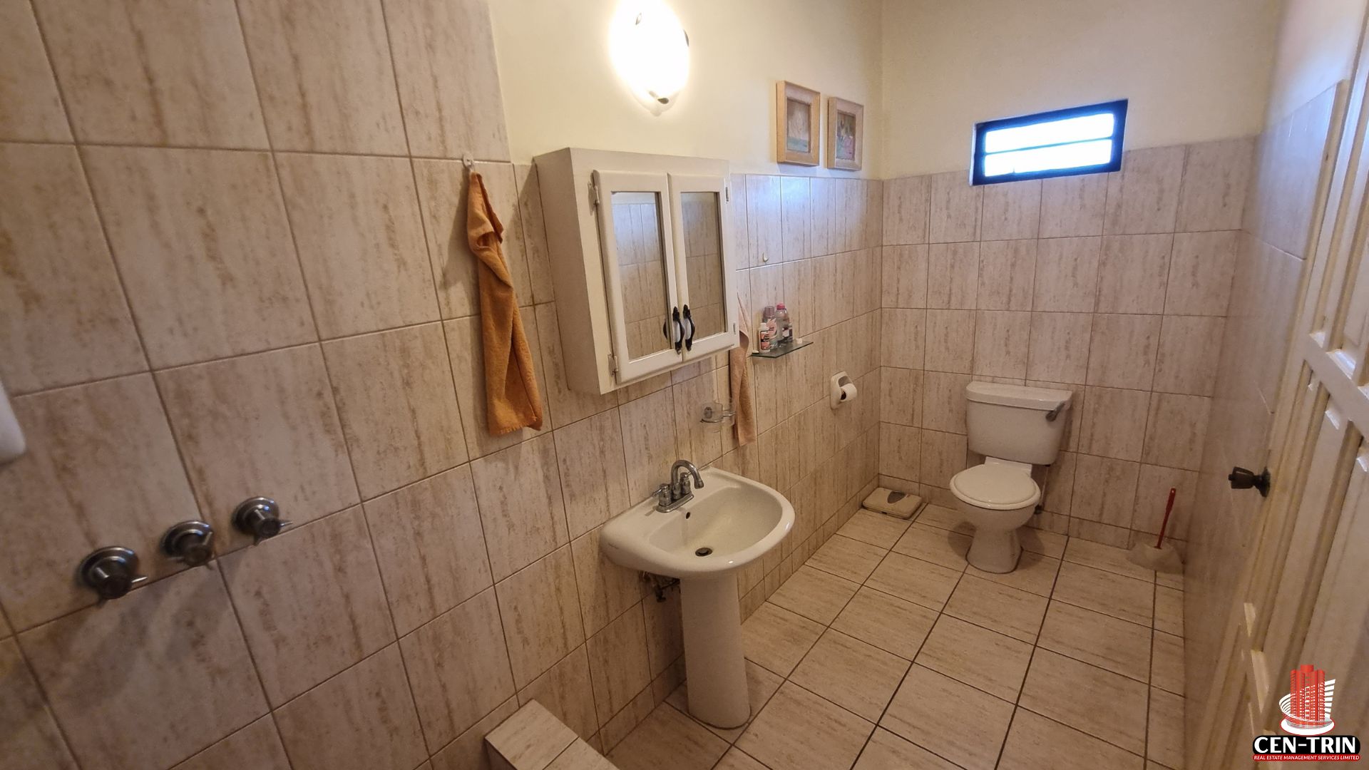 Another well-maintained bathroom in this Home For Sale in Trinidad, featuring a pedestal sink, toilet, and tiled surfaces, ideal for semi furnished units and enhancing rental investment appeal.