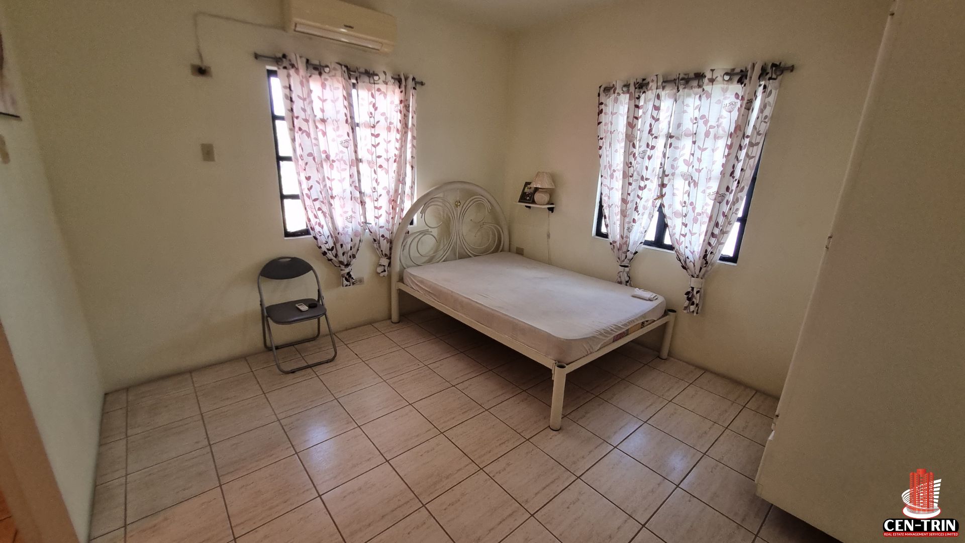Another comfortable bedroom in this Home For Sale in Trinidad, featuring a bed, air conditioning, tiled floor, and two windows, ready for semi furnished setup and offering rental investment potential.
