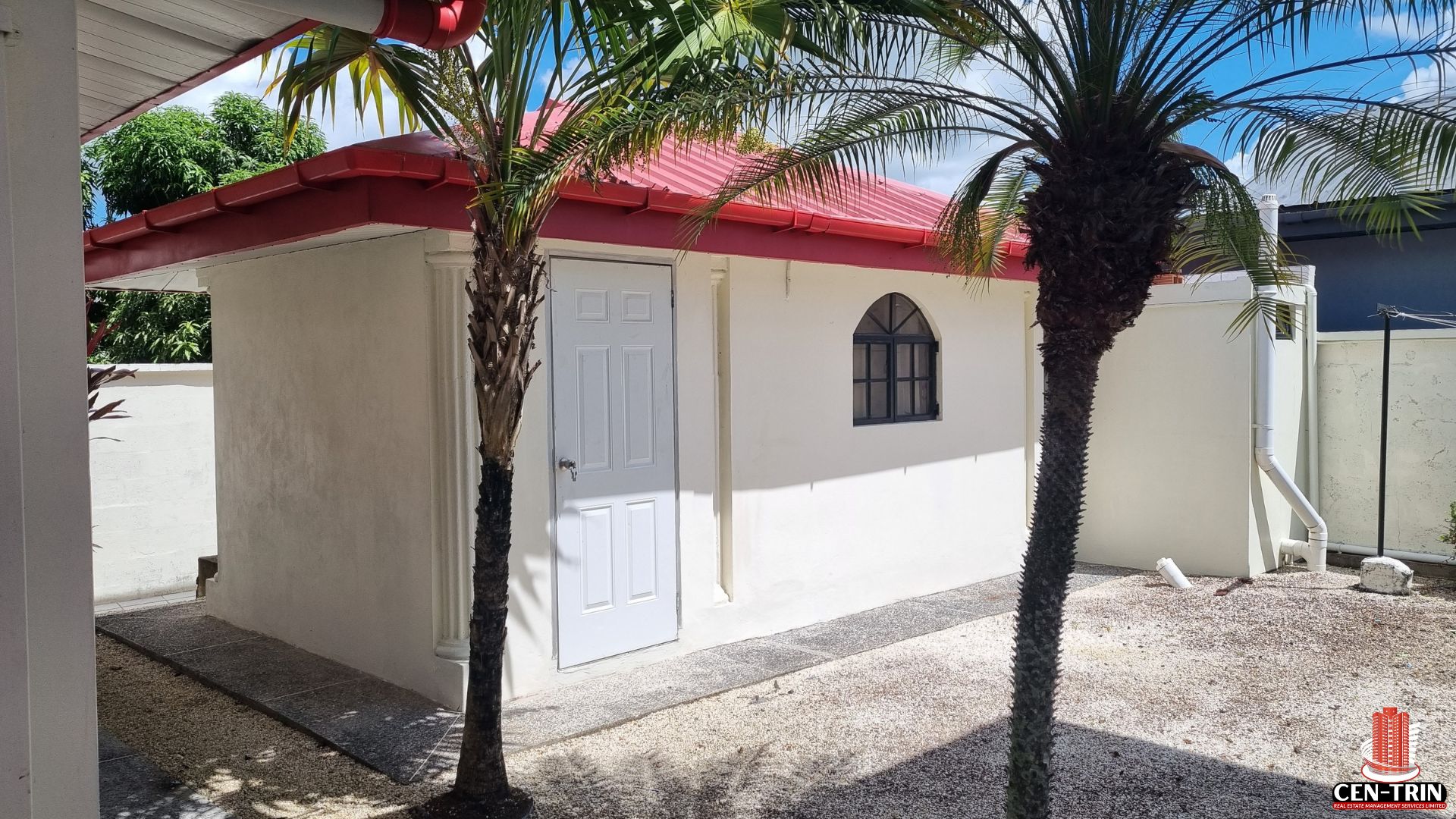 Exterior view of a smaller, separate unit on the property, part of a Home For Sale in Trinidad, with a white door and window, highlighting additional space for semi furnished rentals and increased rental investment.