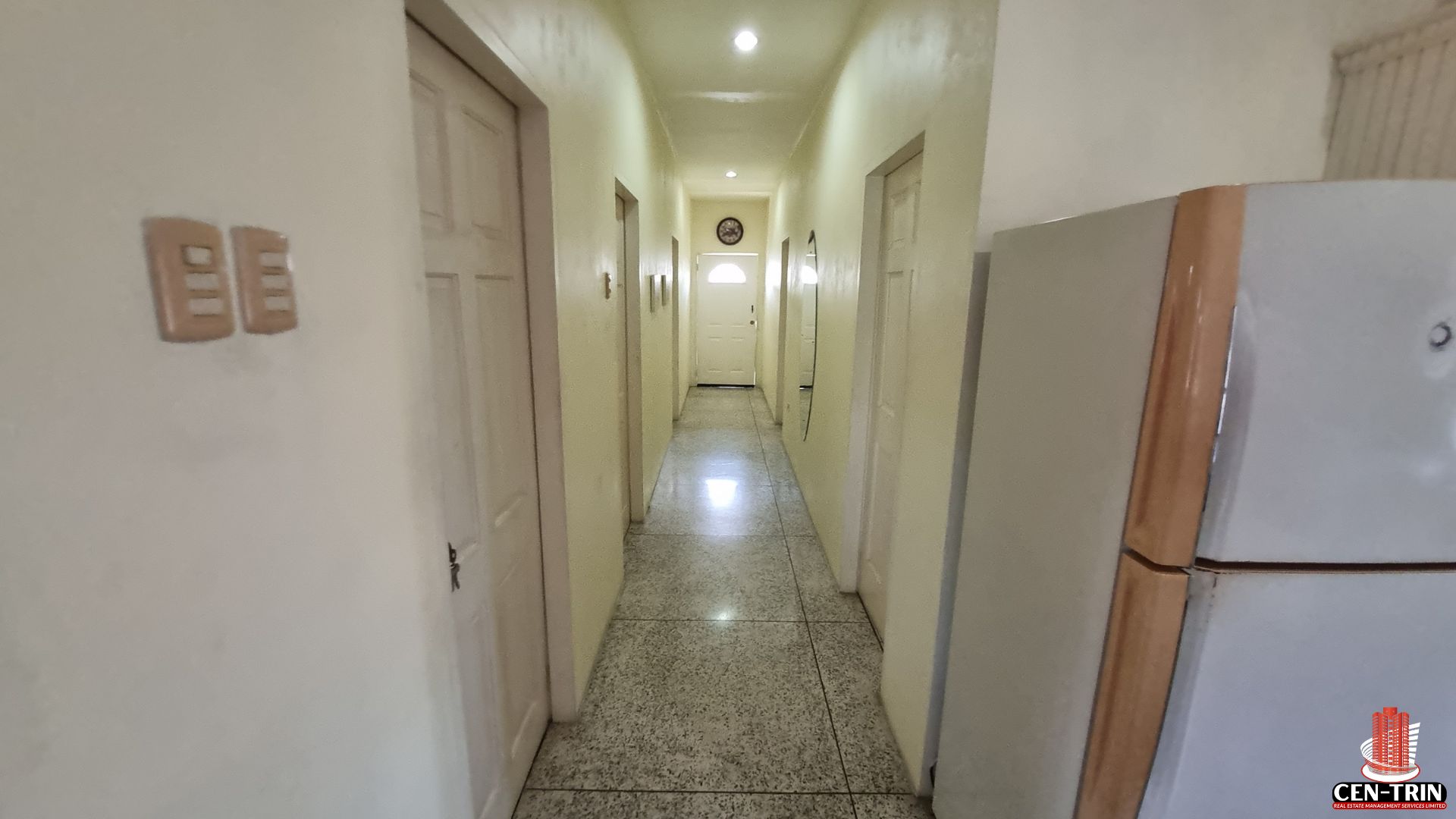 Interior hallway of an apartment building for sale in Chaguanas, showing tiled floors, multiple doors to units, and a long corridor, highlighting areas ready for semi furnished living as a rental investment.