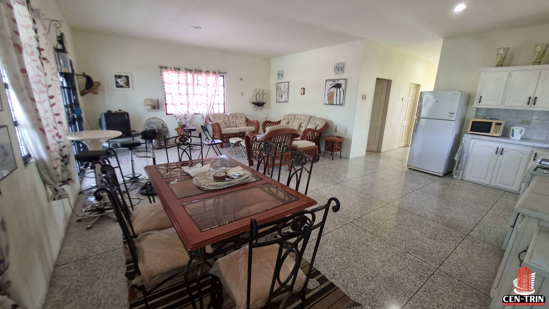 Spacious open-concept living and dining area in a Home For Sale in Trinidad, with dining table, living room furniture, and a partial view of a kitchen, suitable for semi furnished setup and rental investment.
