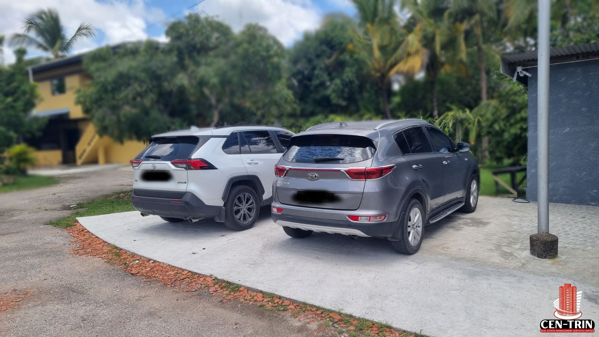 A view of the designated parking area for the commercial rental property on Chin Chin Road, with two SUVs parked on a concrete pad.