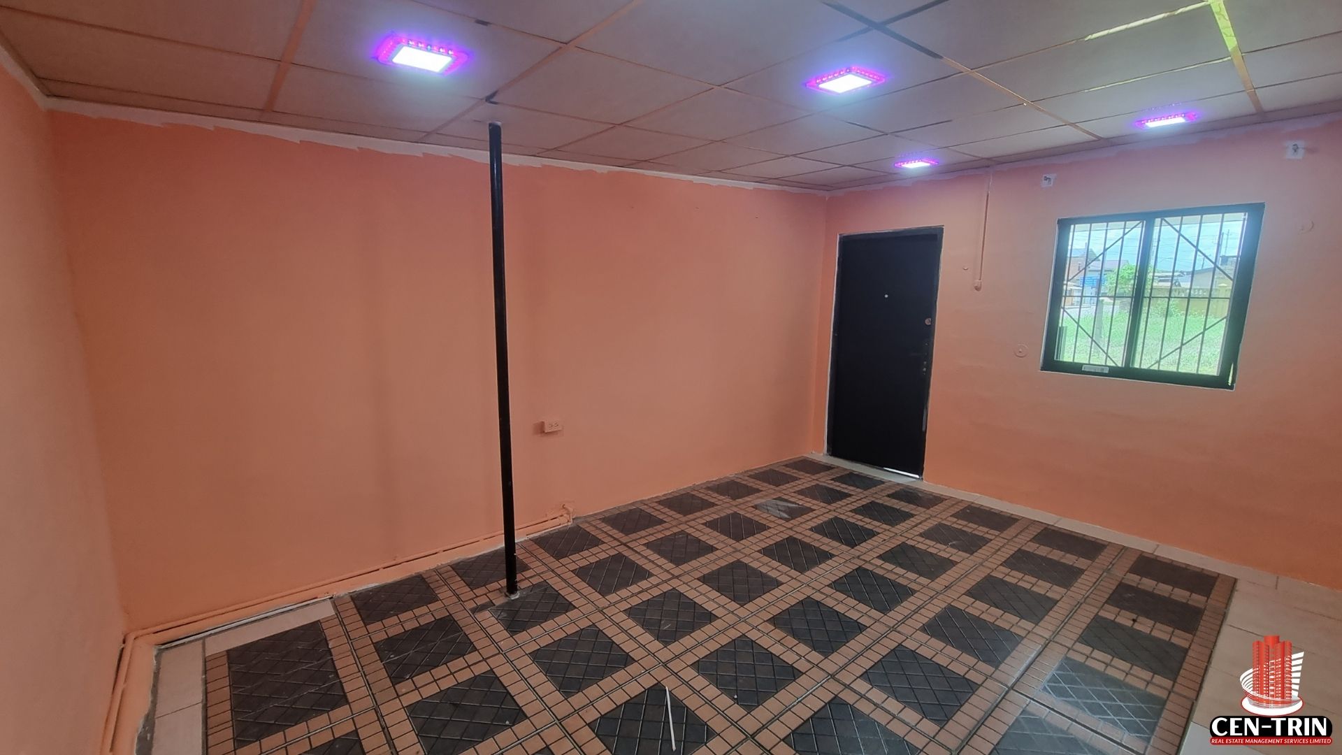 The interior of the commercial rental property on Chin Chin Road, showing a tiled floor, orange walls, and modern ceiling lights.