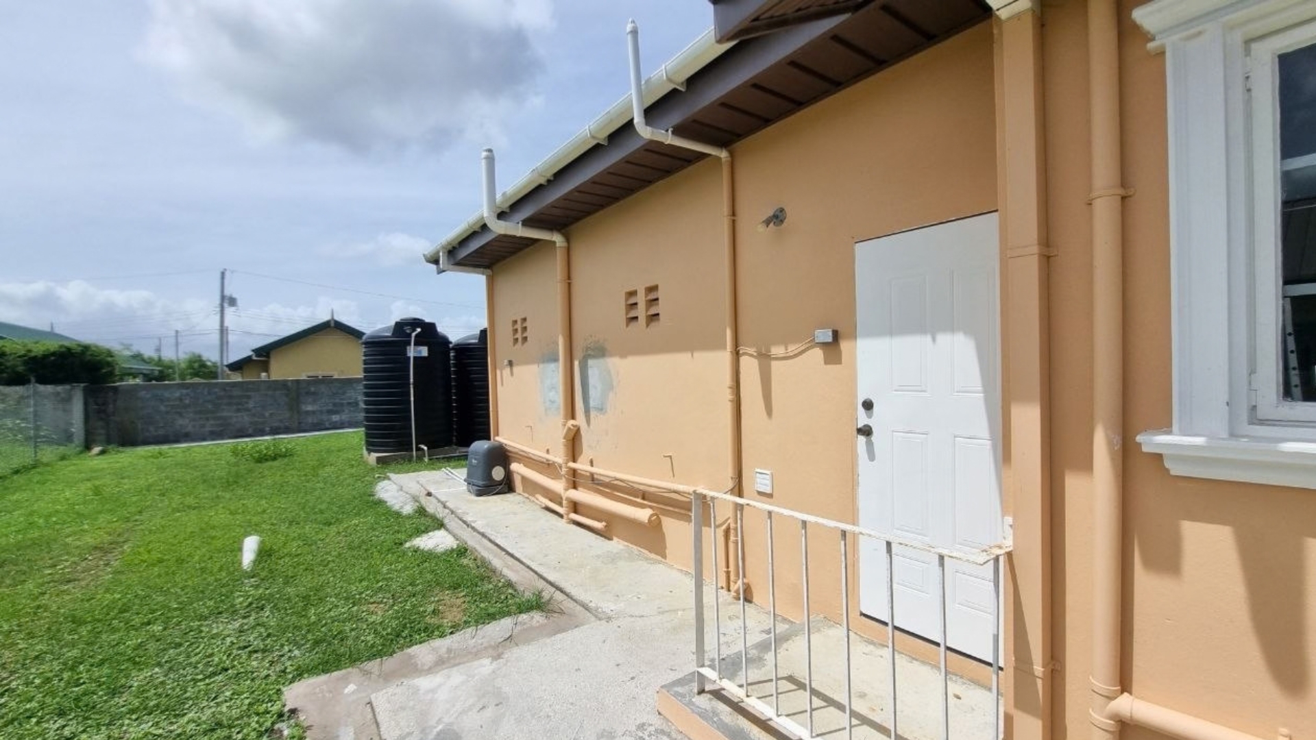 House for Rent | Eden Gardens, Freeport Side Compound Side yard walkway and WASA water storage tanks for house for rent in Eden Gardens Freeport